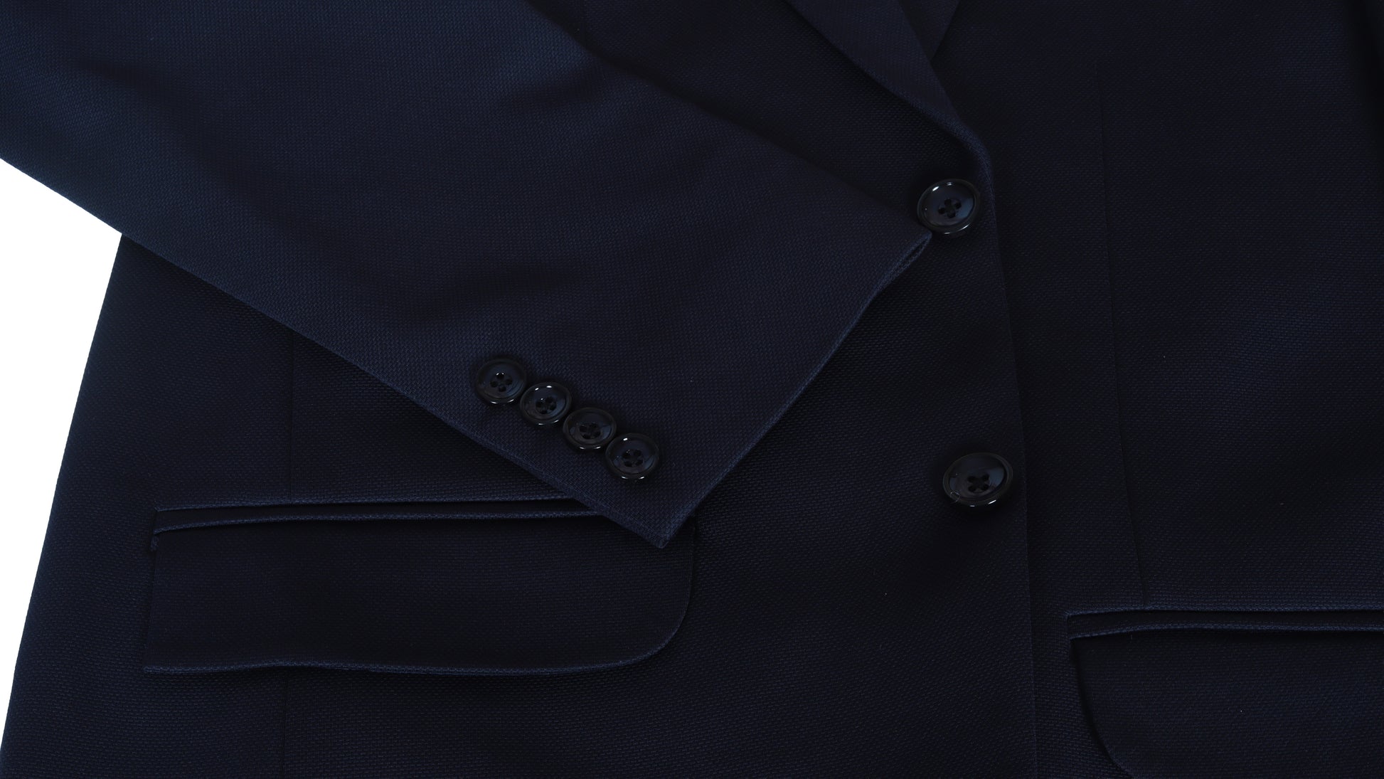 Close-up of a dark blue suit jacket sleeve with buttons on a white background